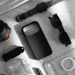 Flat-lay of Nimbus9 iPhone 17 case and accessories on a workbench, in monochrome, highlighting slim MagSafe-ready design.